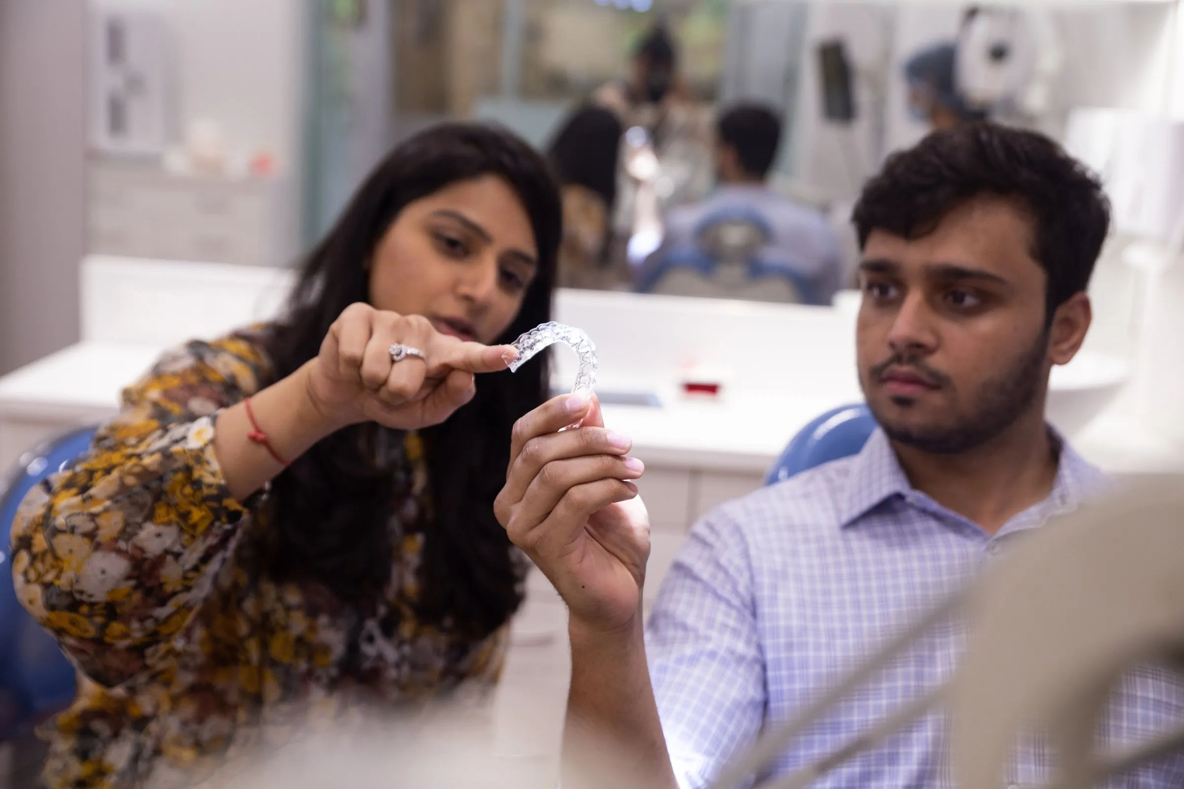 Dr. Upasana Gosalia showing a clear aligner tray to a patient at i-Smile Dental Clinic, Ghatkopar East