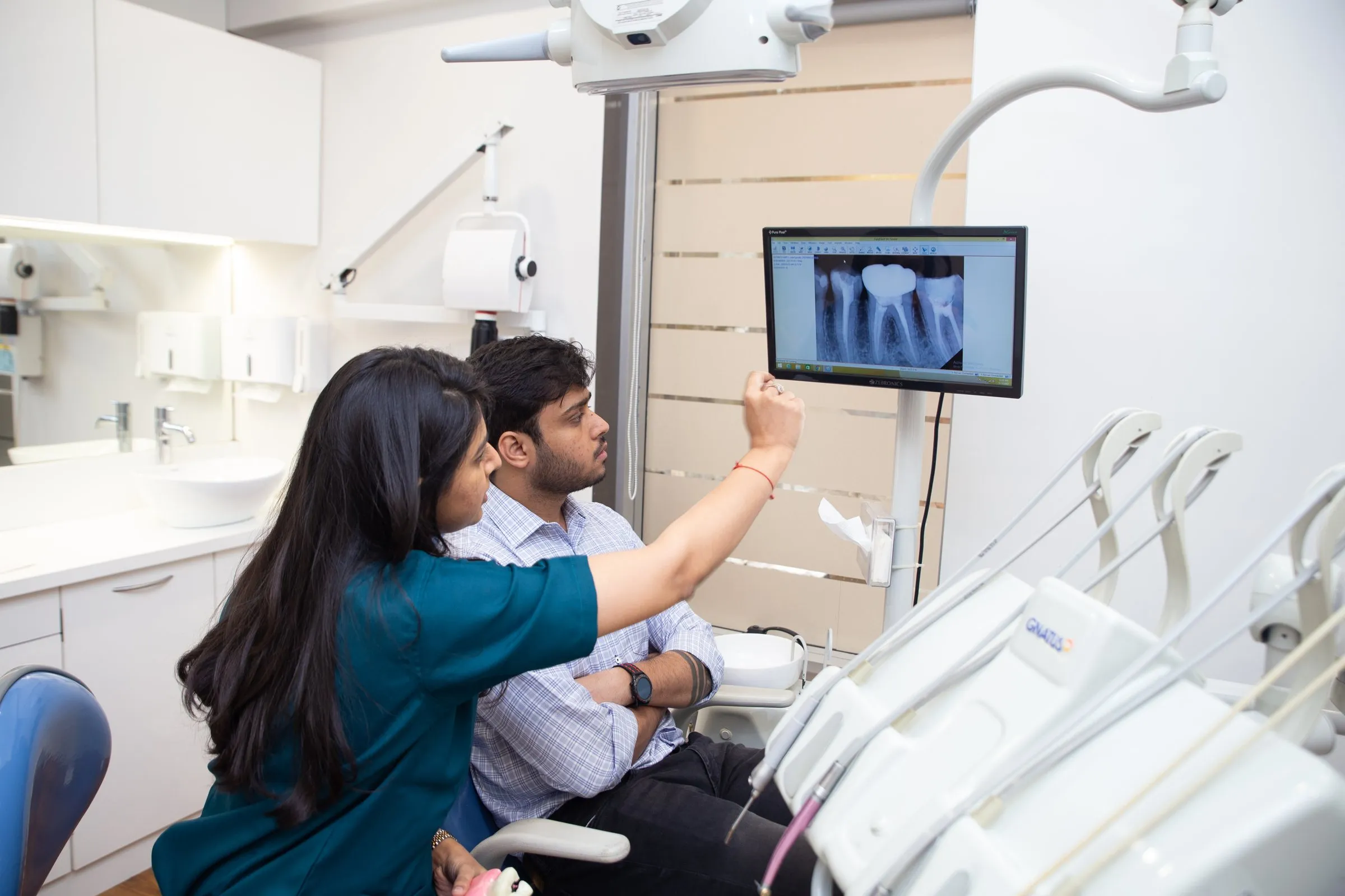 Dr. Upasana Gosalia reviewing a digital X-ray with a patient before dental implant treatment